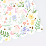 A white paper napkin with a scalloped edge, patterned with pastel unicorns, colorful flowers, and butterflies.