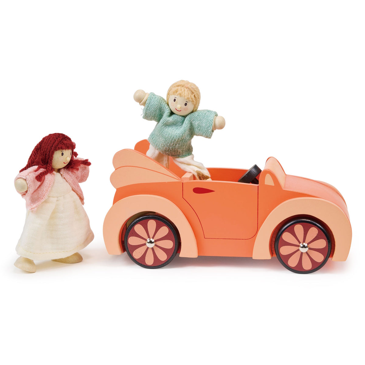 Wooden doll playing inside an orange toy car with flower-patterned wheels.