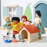 Wooden doll family with a doghouse, toy dog, and cat outside a dollhouse.