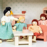 Wooden doll family interacting inside a miniature living room setup.