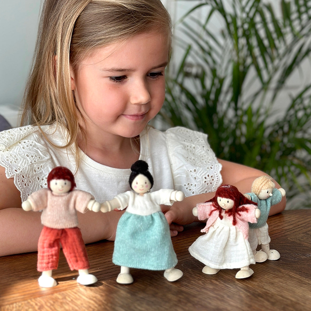 Young girl playing with wooden doll family figures.