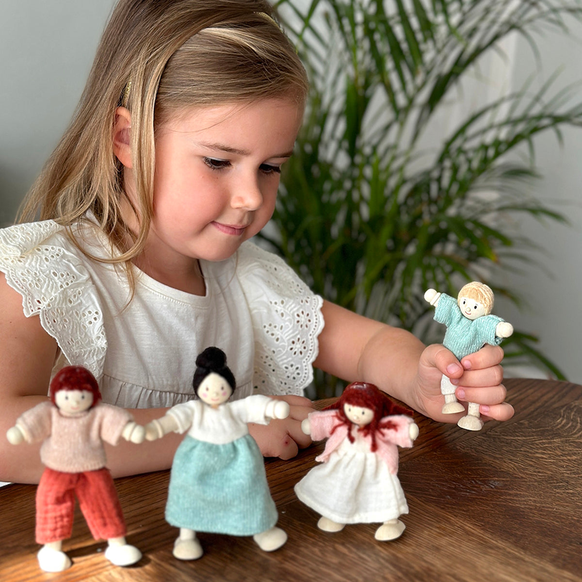 Young girl playing with wooden doll family figures.