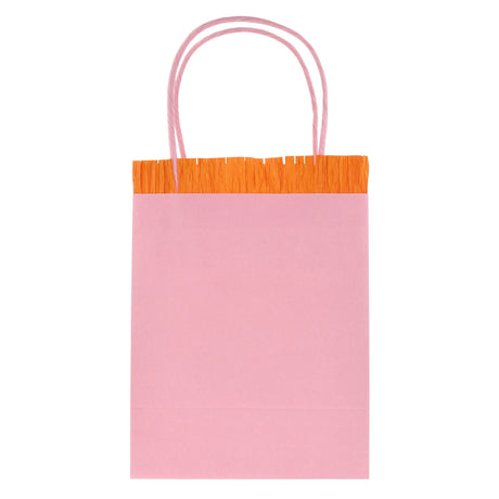 Light pink Meri Meri party gift bag featuring orange crepe paper fringe and pink twine handles on a white background.