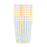 Stacked Meri Meri birthday paper cups with blue, pink, and yellow stripes, gold stars, and "Happy Birthday" text.