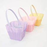 Three pastel crepe paper Easter baskets in purple, pink, and yellow with matching handles for spring celebrations.