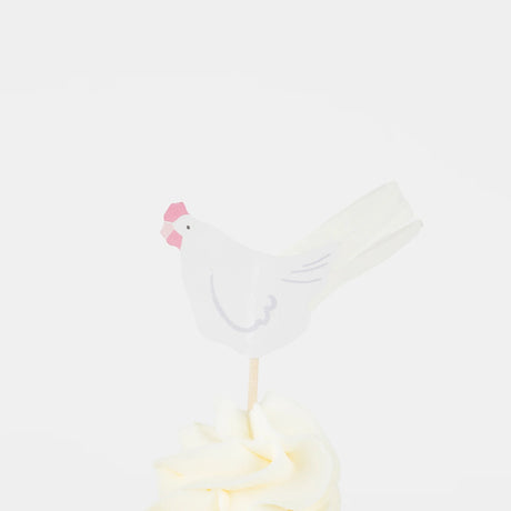 White paper hen cupcake topper with a pink comb on a wooden pick, set in white frosting. Simple Easter party decor.