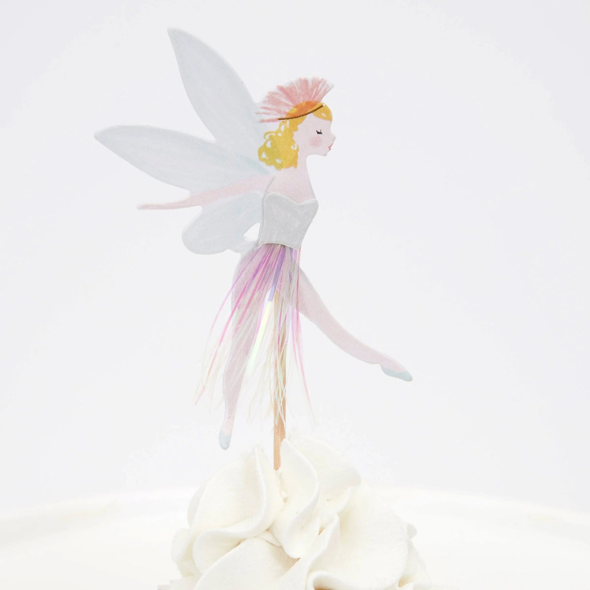 Fairy cupcake topper with wings, a pink tassel skirt, and blonde hair, standing on white frosting.