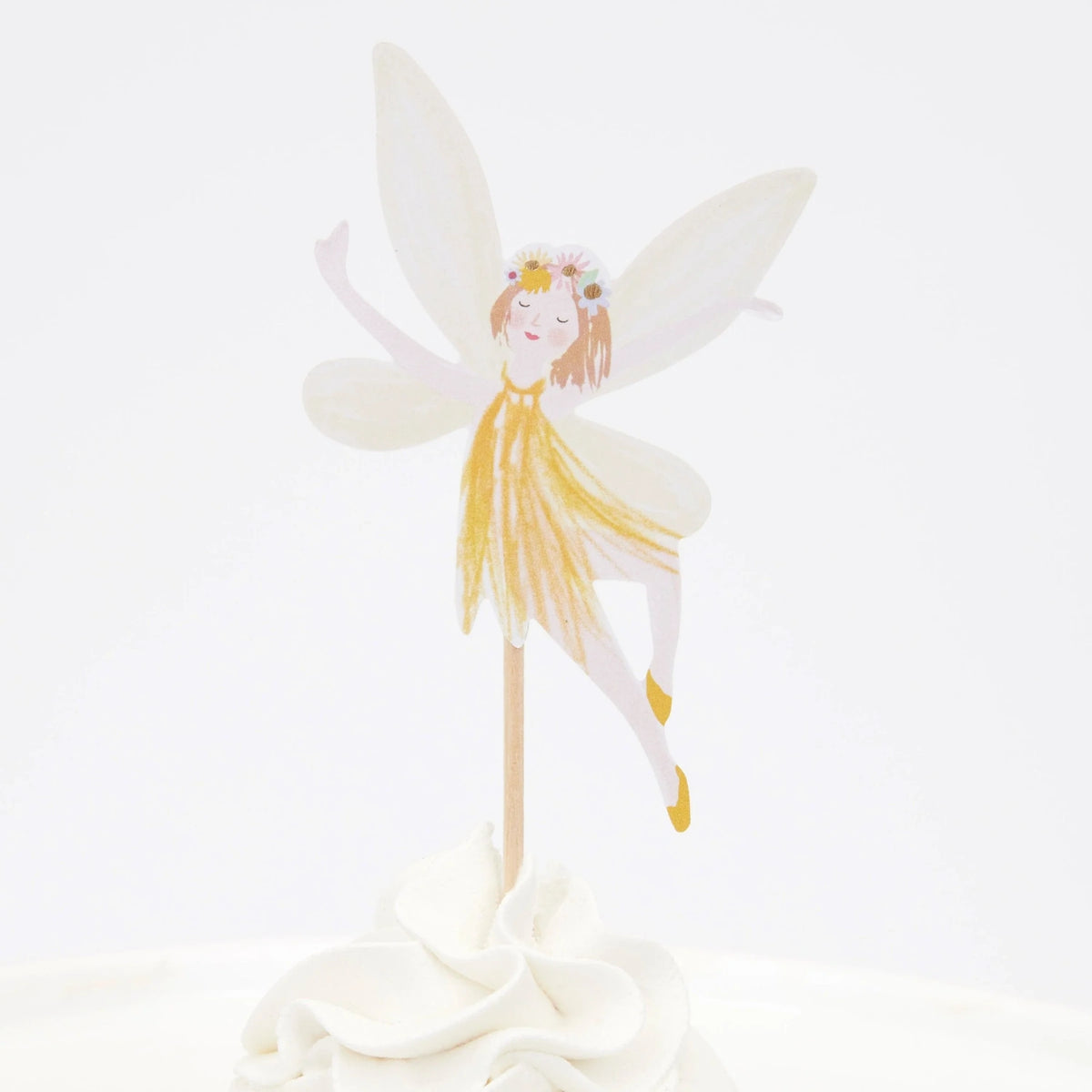 Fairy cupcake topper with white wings, a yellow dress, and a flower crown, placed in white frosting.