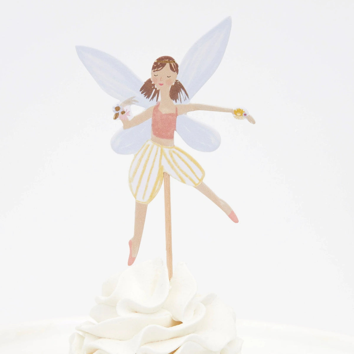 A fairy cupcake topper with wings, a pink top, and striped shorts, stuck into white frosting.