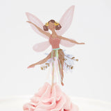 A fairy cupcake topper with pink wings and a tinsel skirt, placed in pink frosting.