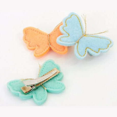 Three Meri Meri felt butterfly hair clips in peach, light blue, and mint green with gold thread antennae.