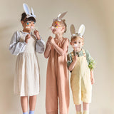 Three children wearing Meri Meri paper bunny ears and holding whiskers, perfect for Easter party costumes and celebrations.