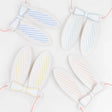 Four sets of pastel striped paper bunny ears with matching bow ties and pink elastic strings on a white background.