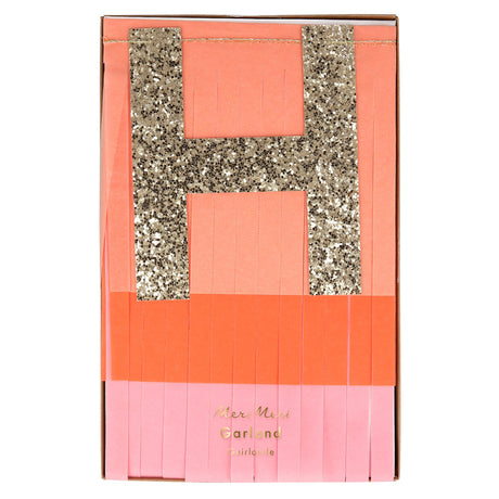Meri Meri pink and peach fringed Happy Birthday garland set featuring a large gold glitter "H" in a gift box.