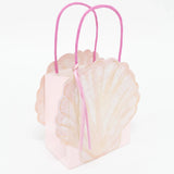 Pink seashell-shaped gift bag with bright pink handles and a small ribbon tassel against a white background.