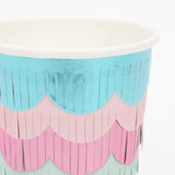 A paper party cup decorated with scalloped layers of metallic blue, pink, and green fringe.
