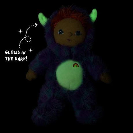 Plush doll in dark showing glow-in-the-dark horns and belly patch with "GLOWS IN THE DARK!" text.