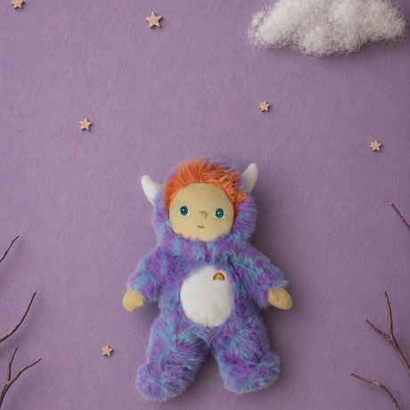Plush doll in a fuzzy purple monster suit on a purple background with small wooden stars and clouds.