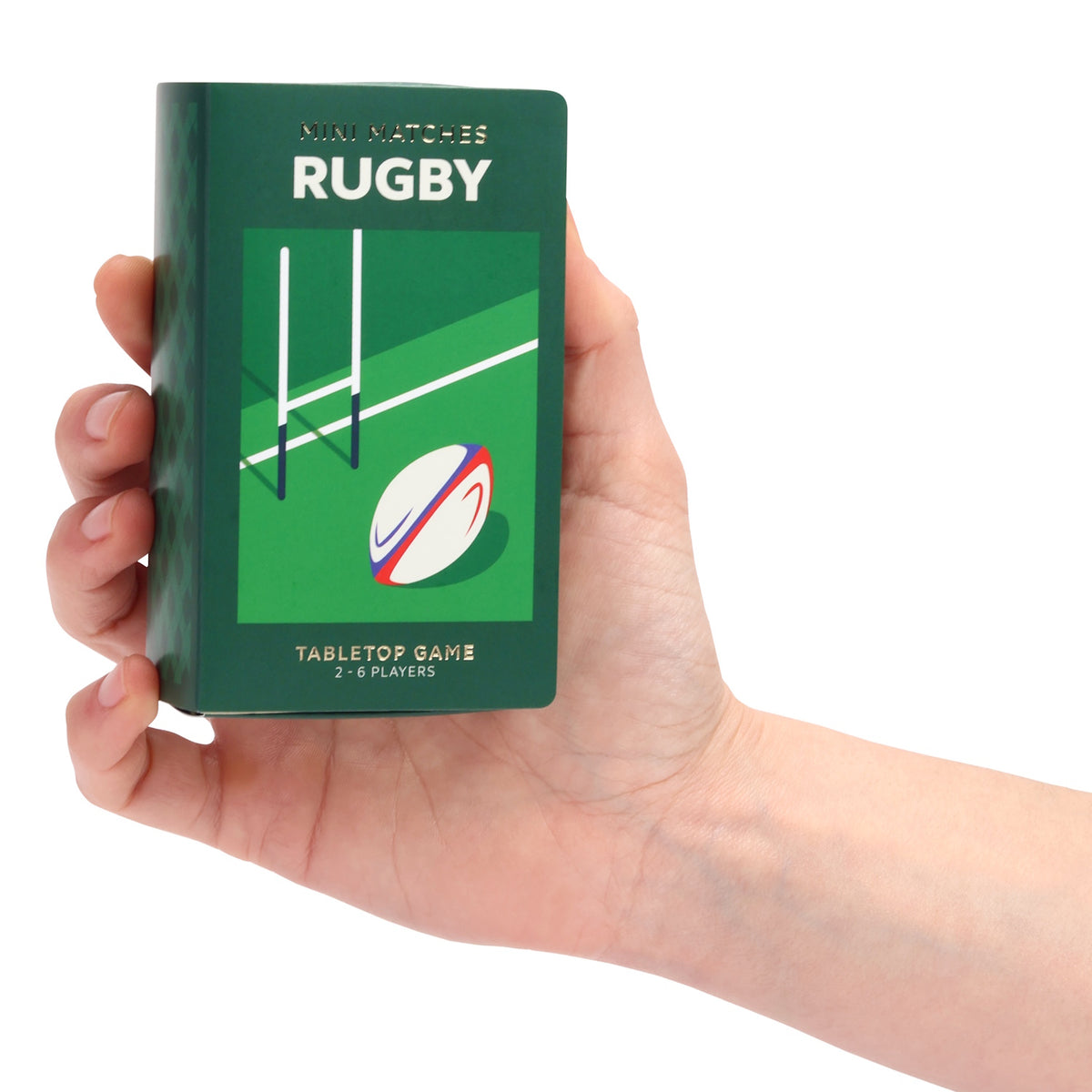 Hand holding a green Mini Matches Rugby tabletop game box against a white background.