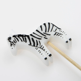 Close-up view of a zebra-shaped birthday candle on a wooden pick.