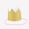 Mini gold glitter party crown with a pink elastic chin band set against a white background.
