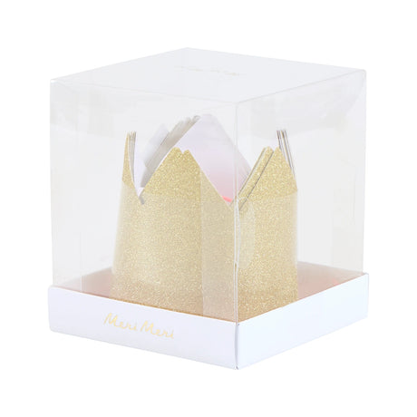 Clear plastic cube box displaying mini gold glitter party crowns inside.