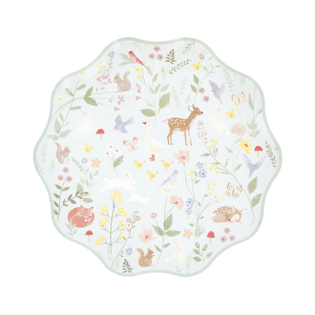 A wavy-edged pastel green paper plate featuring a delicate woodland animal and wildflower pattern.