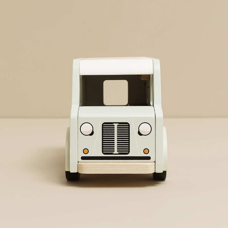 Front view of light green and white wooden toy café van on a beige background.