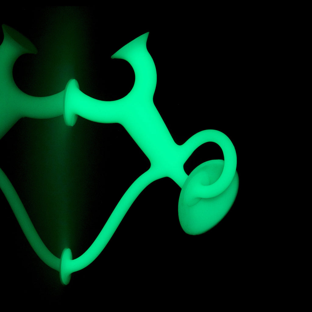 Glowing abstract green object with curving lines and loops on a black background, creating a mysterious and futuristic atmosphere.
