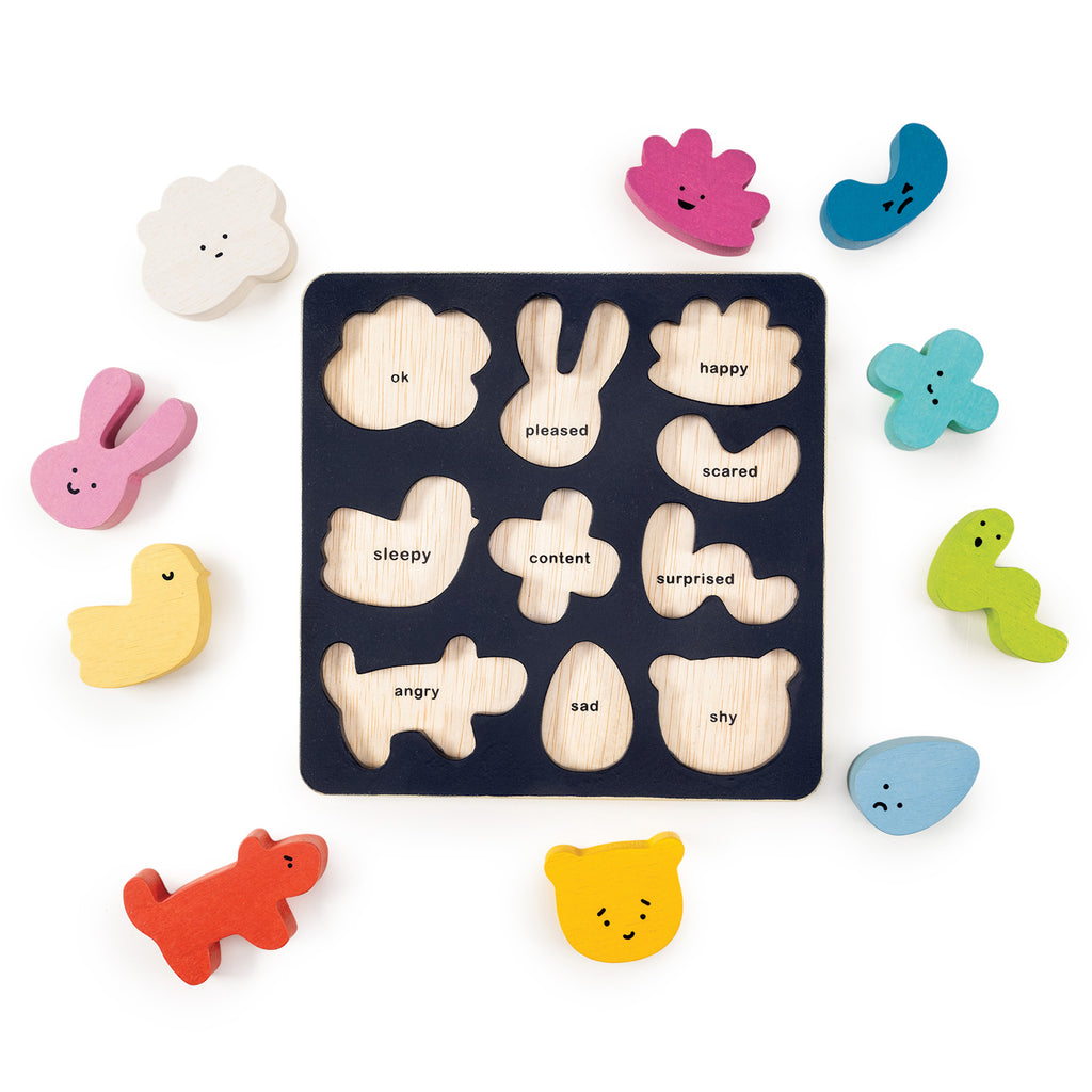 Wooden puzzle board with various shapes labeled with emotions like happy and sad. Brightly colored pieces with faces surround the board, evoking playfulness.