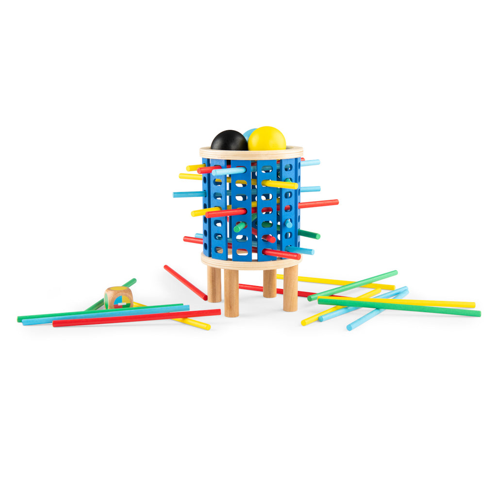 Colorful toy resembles a wooden barrel with holes, containing black and yellow balls. Multicolored sticks protrude, with some scattered around. Playful tone.