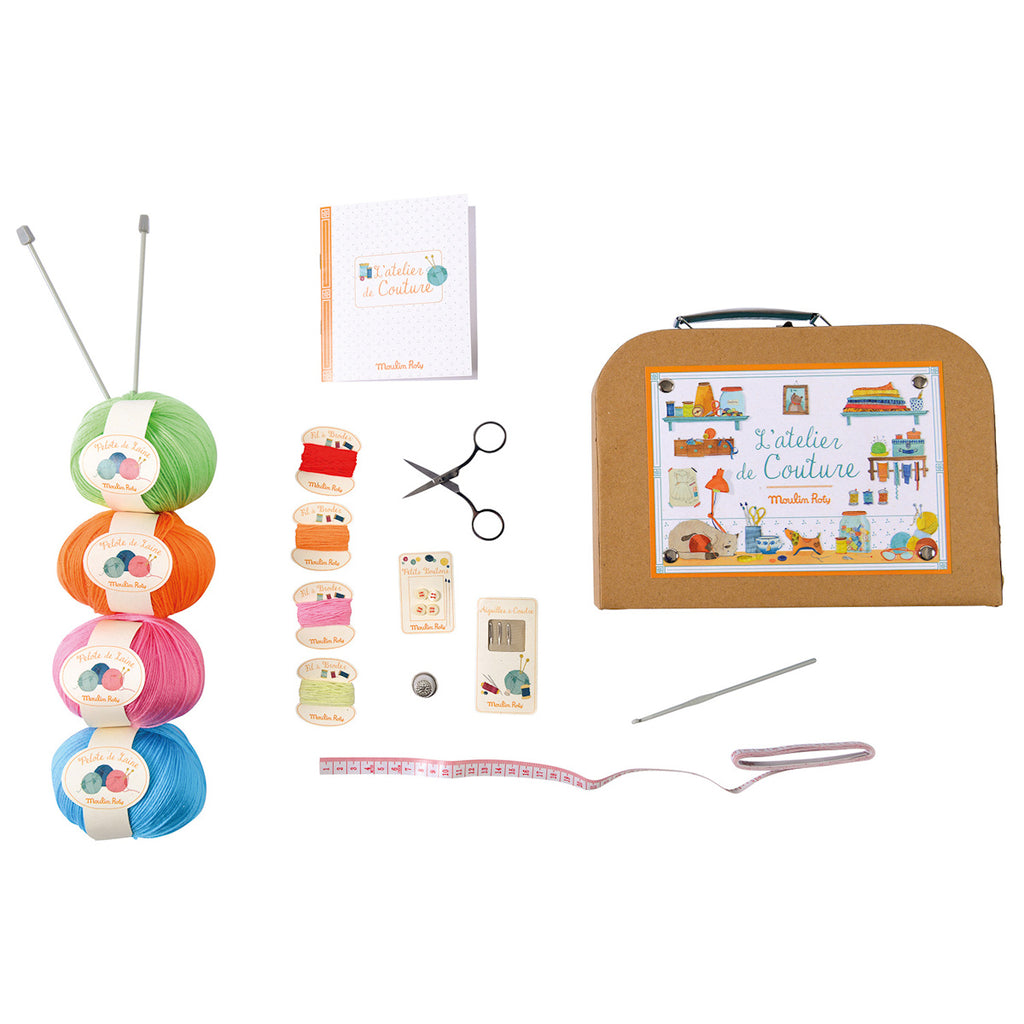 Craft kit with colorful yarn balls, scissors, a small notebook, measuring tape, and a box labeled "L'atelier de Couture." Playful and creative vibe.