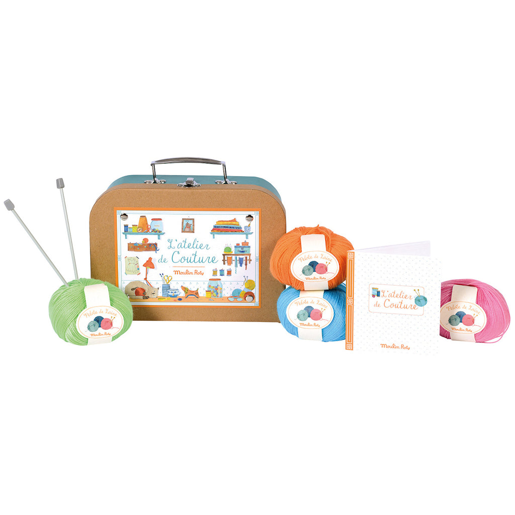 Craft kit with colorful yarn balls, scissors, a small notebook, measuring tape, and a box labeled "L'atelier de Couture." Playful and creative vibe.