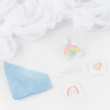 Unwrapped surprise ball contents including a joke slip, rainbow figure, temporary tattoos, tissue paper, and white streamer background.