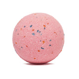 A pink bath bomb with blue and orange speckles, against a plain white background. The item appears textured, evoking a sense of relaxation and self-care.