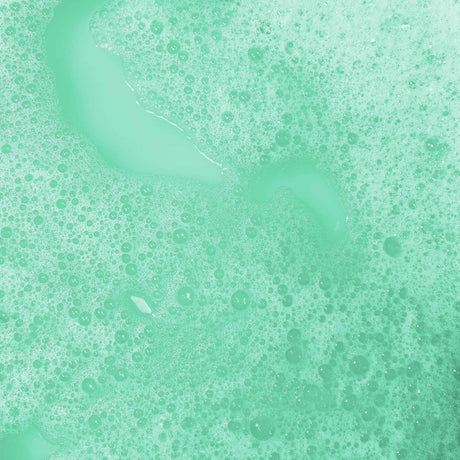 Green foamy bubbles cover a liquid surface, creating a textured and calming pattern. The soothing mint color evokes freshness and cleanliness.