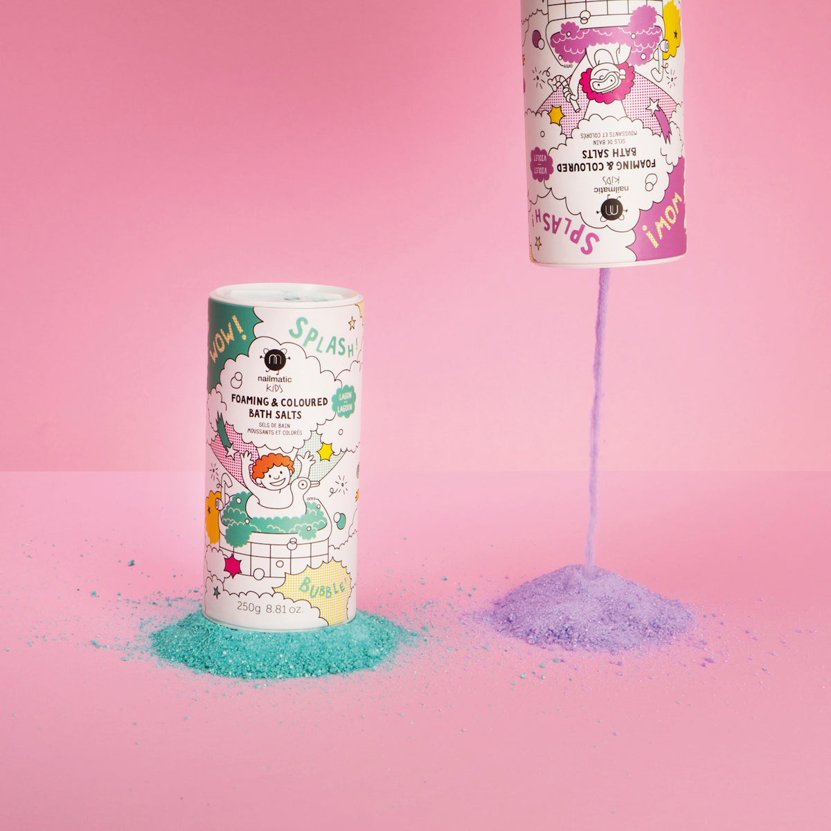 Two playful containers of foaming bath salts against a pink backdrop; one is upright with green salts, the other upside down pouring purple.