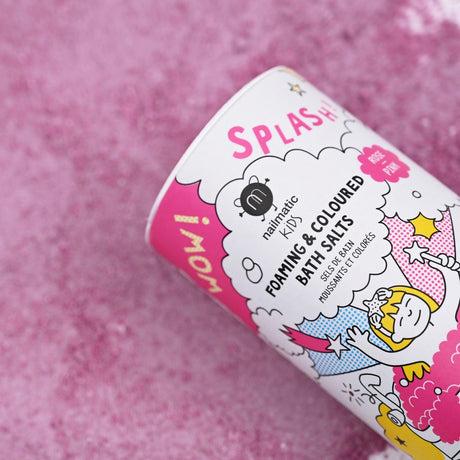Colorful canister of Nailmatic Kids foaming bath salts on a pink textured surface. Features playful illustrations and bright, cheerful design.