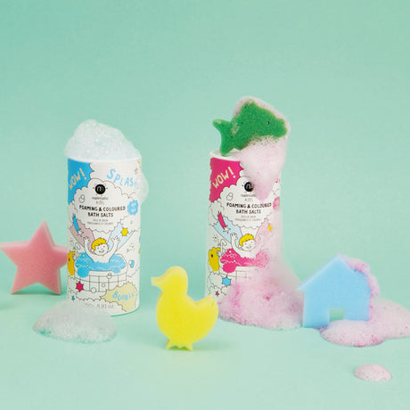 Two colorful bath salt containers with foam, adorned with playful illustrations, are surrounded by a pink star, yellow duck, and blue house sponges.