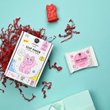 Colorful DIY soap kit for kids with cartoon cat illustrations on the box. Includes a red cat soap mold, white soap packet, and red crinkle paper on a turquoise background. Playful and creative tone.