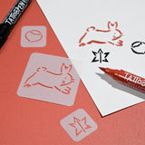 Stencil art supplies on red paper and white card. Includes a bunny and star stencil, used with black and red markers for tattoo designs.