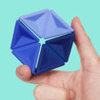 A hand holding a blue silicone hexaflexagon fidget toy against a light teal backdrop.