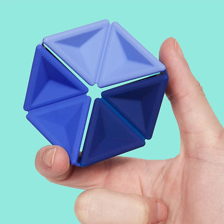 A hand holding a blue silicone hexaflexagon fidget toy against a light teal backdrop.