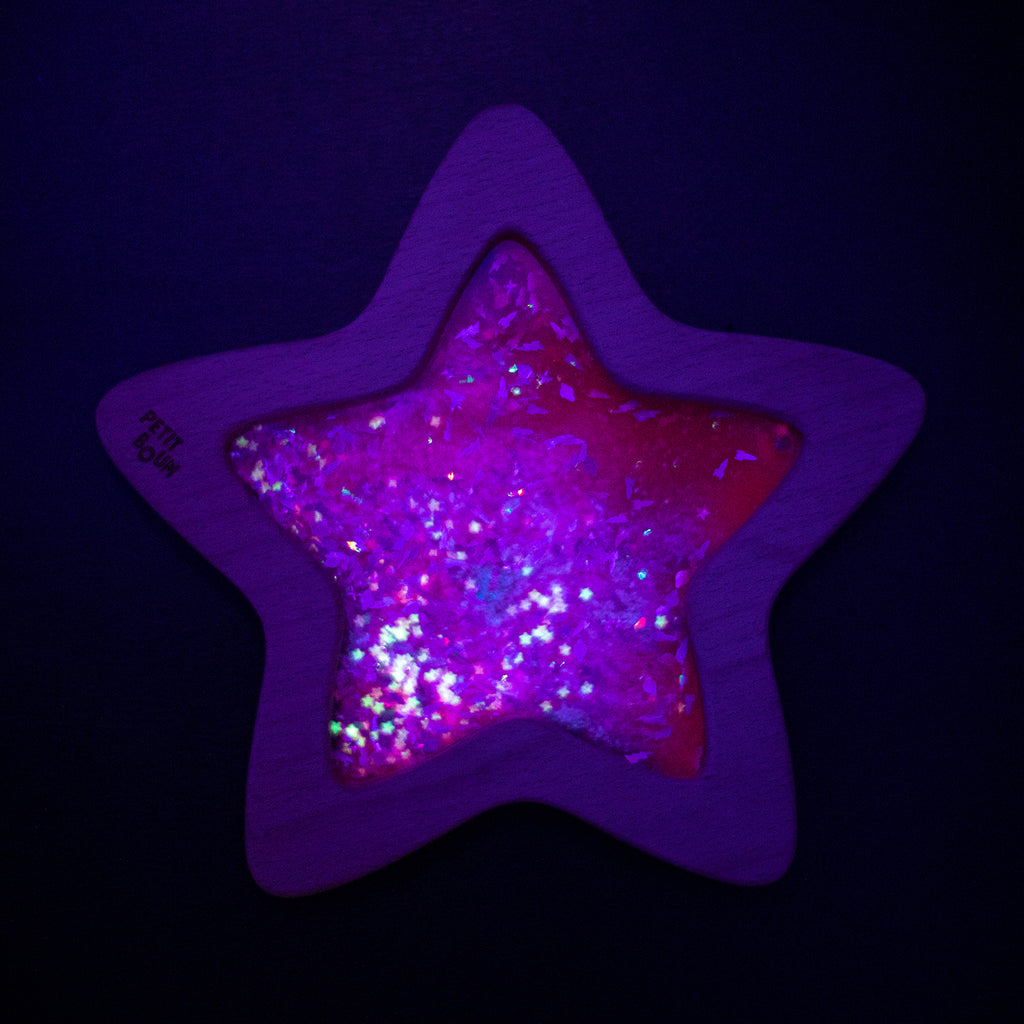 The Flow Star sensory toy glowing in the dark, revealing its sparkling and luminescent effect.
