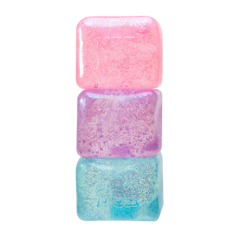 Stack of three colorful gel cubes with glitter: pink on top, purple in the middle, and blue at the bottom. Shiny and playful texture conveys a whimsical tone.