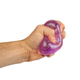 A hand squeezes a purple glittery stress ball against a white background. The texture is shiny and squishy, creating a sense of playful relaxation.