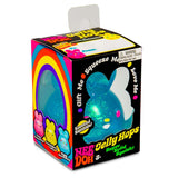 Packaging for a Nee Doh Jelly Hops toy featuring a blue glittery bunny with a rainbow design. Text: "Squeeze Me" and "Scented Bunnies." Fun, playful tone.