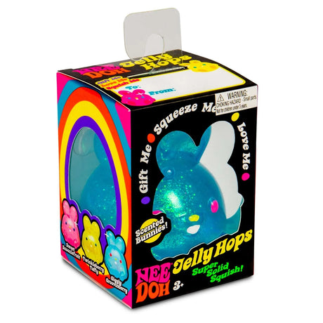 Packaging for a Nee Doh Jelly Hops toy featuring a blue glittery bunny with a rainbow design. Text: "Squeeze Me" and "Scented Bunnies." Fun, playful tone.