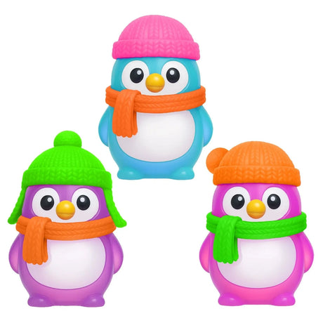 Three colorful NeeDoh Polar Glow Penguin squishy fidget toys in blue, purple, and pink with knit hats and scarves.