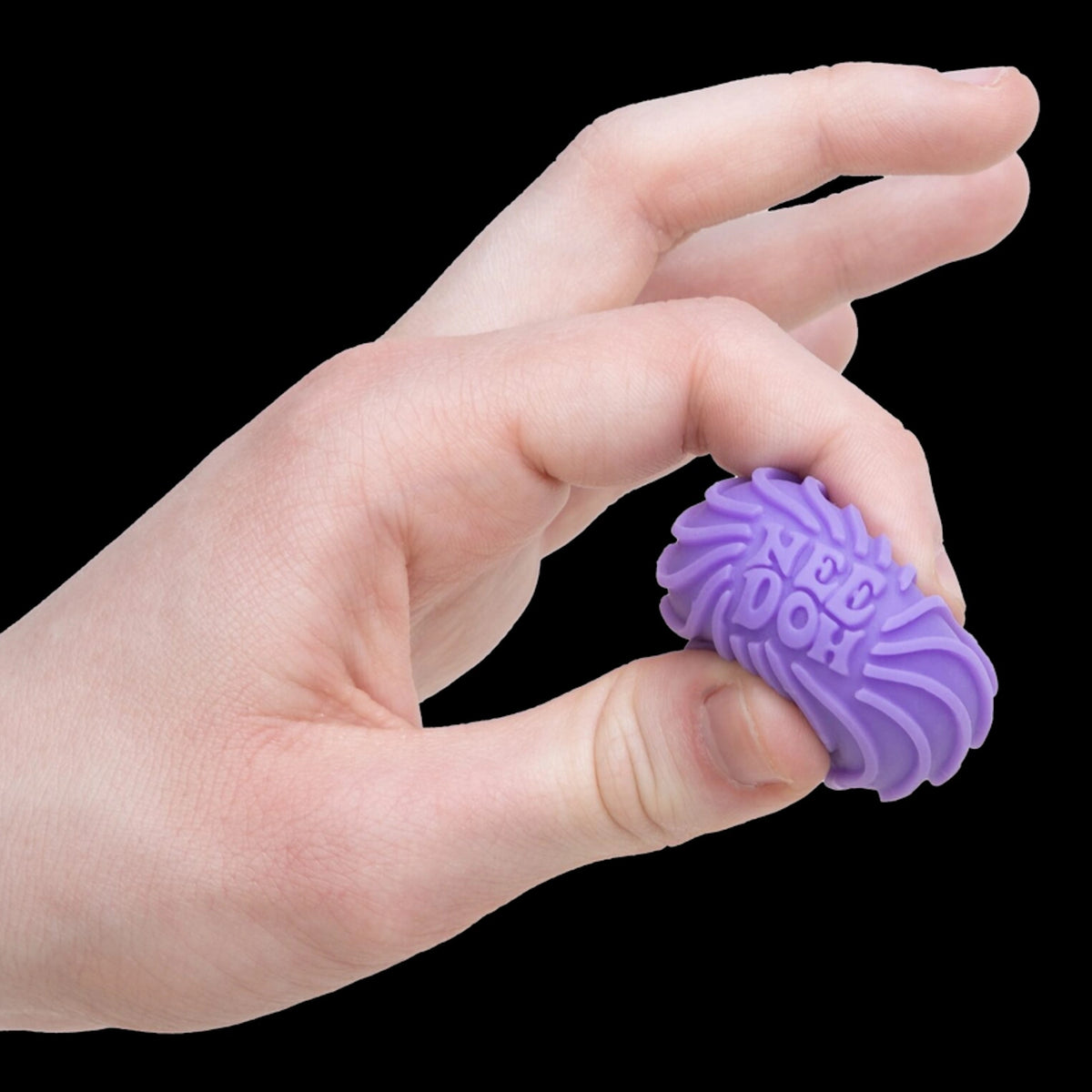 A hand gently squeezes a small, purple, textured fidget toy labeled "Nee-Doh" against a black background, conveying a sense of calm and focus.